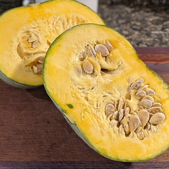 kabocha squash cut in half on cutting board